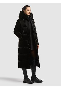 Melna pūkaina jaka ar augstu apkakli, šūts raksts un priekšējā rāvējslēdzēja. Aprīkota ar sānu kabatām un garumu līdz ceļiem, saskaņota ar zābakiem līdz ceļiem.