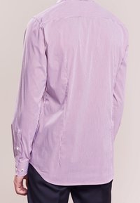 Randig skjorta med knappar i ljus lila, med vertikala vita ränder, långa ärmar och manschettknappar. Slät, lättviktig tyg.