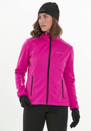 Roze softshell jack met zwarte ritszakken, zilveren accenten en een hoge kraag. Geselecteerd samen met zwarte handschoenen en een broek voor buitenactiviteiten.