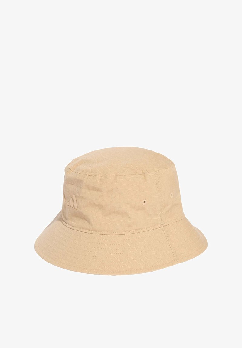 Bežový kbelíkový klobouk vyrobený z texturované látky, s plochým vrškem, širokým krempou a jemným logem na boku.