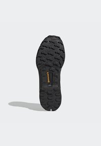 Suela de zapato de goma negra con patrones de diseño profundo, presentando lugs hexagonales para tracción y un logo amarillo de Continental cerca del talón.