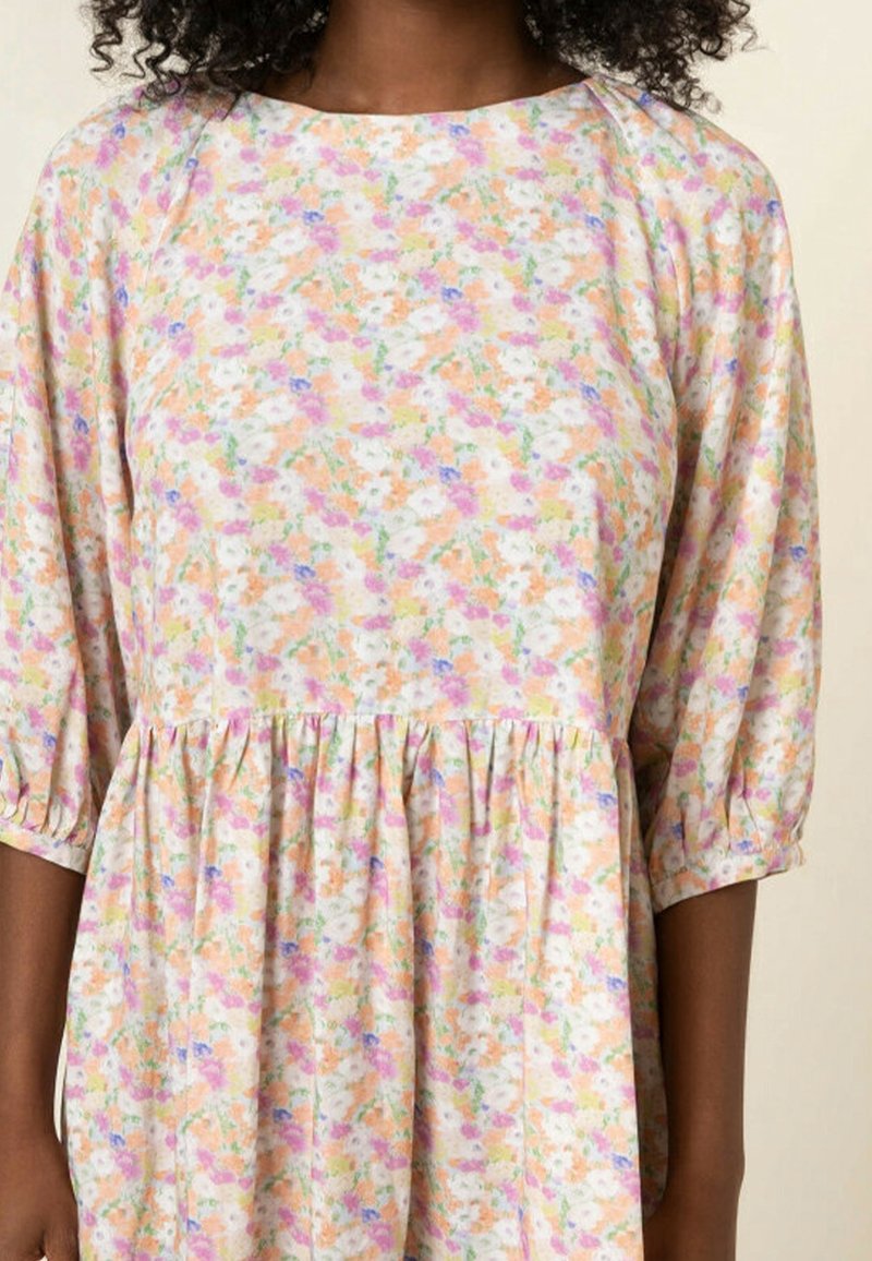 Robe à imprimé floral avec manches raglan, encolure ronde, taille froncée et tissu doux dans des tons pastel de rose, orange et blanc.