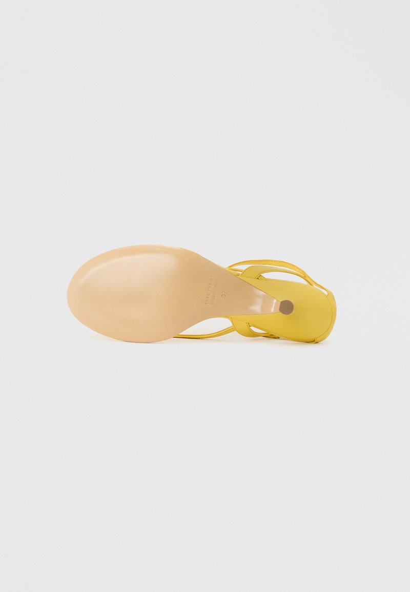 Sandalia de tacón alto amarilla con una superficie lisa y brillante, diseño de punta abierta y correas delgadas. La suela es de color nude y presenta una forma redondeada.