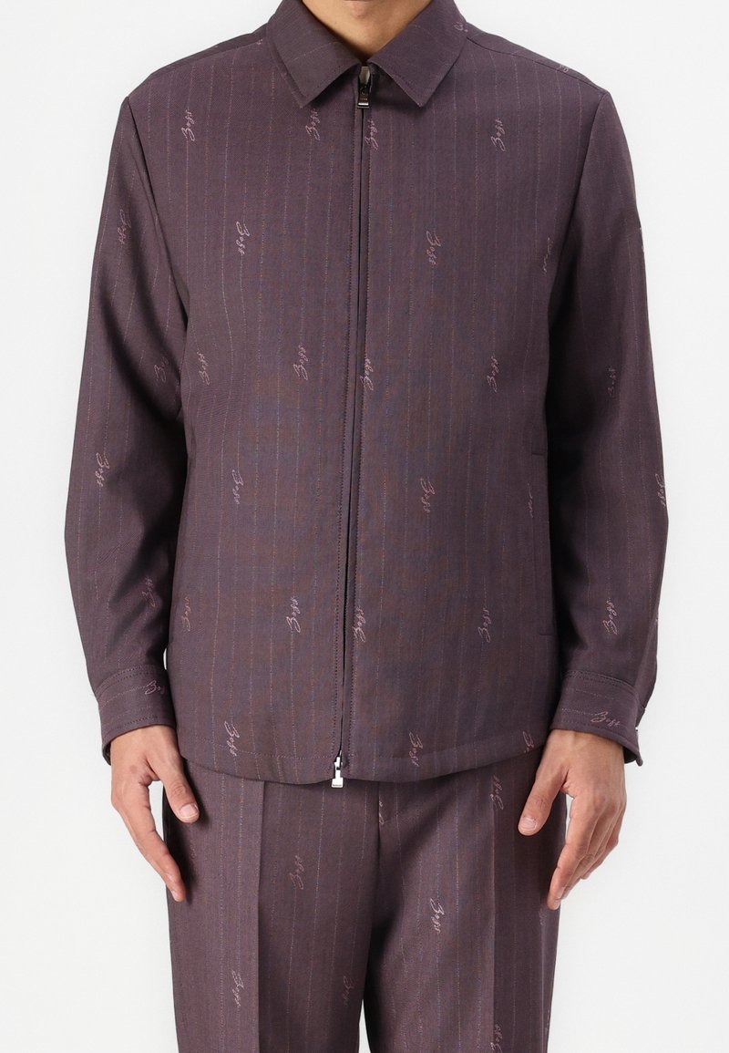 Purple zip-up jacket with a contrasting pinstripe pattern and small logo accents, featuring a spread collar and long sleeves.