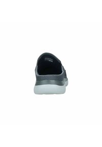Black mesh sneaker with a textured heel, featuring a white rubber sole and minimalistic design. Back view highlights the rounded shape.