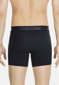 Svarta boxerkalsonger tillverkade av ett mjukt tyg, med en mjuk midjeresår med präglad logotyp, som har en åtsittande design och slutar vid mitten av låret.