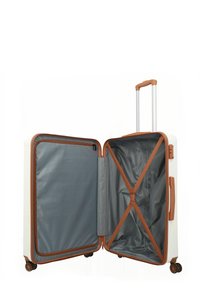 Valise rigide blanche avec des accents marron, deux roues, une poignée rétractable et des compartiments intérieurs gris avec des sangles élastiques.