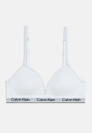 Biely bezdrôtový podprsenka Calvin Klein s nastaviteľnými ramienkami a značkovým elastickým pásom v dolnej časti na jednoliatej pozadí.