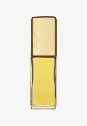 Żółta szklana butelka na perfumy w kształcie prostokąta, z złotą pokrywką grawerowaną nazwą marki. Przezroczysta podstawa eksponuje ciecz w środku.