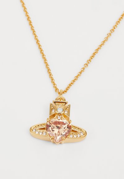 Gul kæde med en hjerteformet pink ædelsten pendant med accentsten og intrikate designelementer over ædelstenen.
