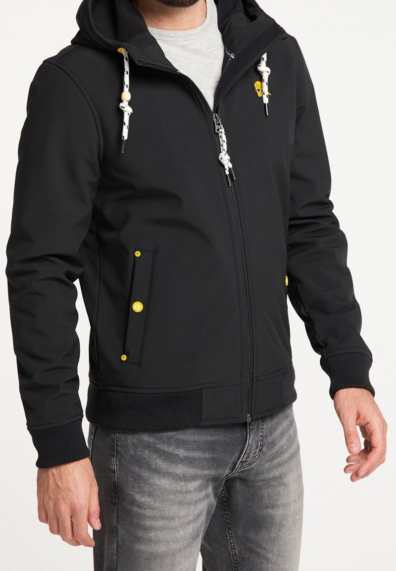 Veste noire avec fermeture éclair, deux poches avant avec boutons jaunes et capuche. Dotée de cordons blancs et noirs, texture douce.