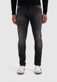 Donkergrijze denim jeans met een slim fit, subtiele vervaging en een klassiek vijf-pocket ontwerp, gecombineerd met witte sneakers.