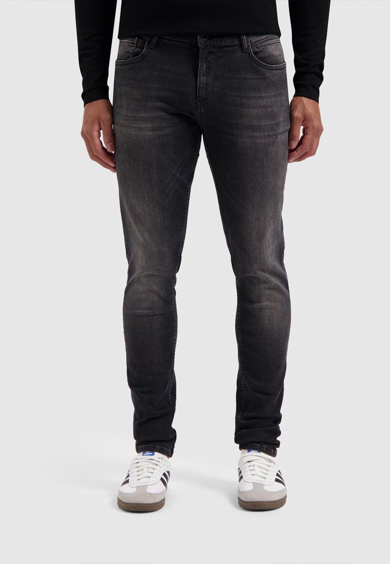 Donkergrijze denim jeans met een slim fit, subtiele vervaging en een klassiek vijf-pocket ontwerp, gecombineerd met witte sneakers.