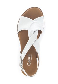 White leather sandal with crossed straps, brown sole, and silver buckle detail. Flat design with a smooth texture and open shape.