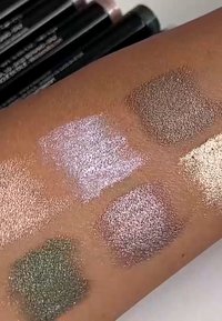 Metalliset luomivärinäytteet iholla: vihreä, pehmeä violetti, vaaleanpunainen ja kaksi kultaruskeaa sävyä. Karkeapintaiset ja hohtavat lopputulokset.