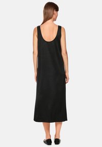 Schwarzes ärmelloses Kleid mit tiefem Rundrücken, aus strukturiertem Stoff gefertigt. Bodenlanges Design mit entspannter Passform und geradem Schnitt.