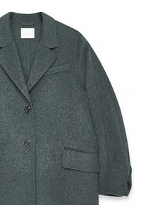 Manteau en laine grise avec un col à revers, deux boutons devant et une poche plaquée. Présente un tissu texturé et une coupe structurée et décontractée.