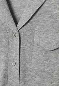 Szürke kötött kardigán gallérral, két gombbal és bal oldali mellzsebbel. Az anyag puha és texturált hatású.