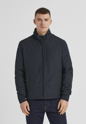 Marineblaue, leichte Jacke mit hohem Kragen, Frontreißverschluss und Seitentaschen. Sie hat eine glatte Textur und elastische Bündchen.