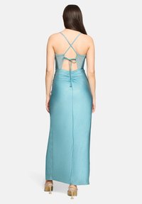 Une longue robe moulante en tissu bleu clair scintillant avec un dos croisé et des détails froncés à la taille.