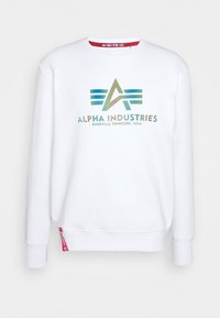 Sweat-shirt blanc à manches longues avec logo et texte Alpha Industries en vert et bleu, "Knoxville, Tennessee, U.S.A.", et une étiquette rouge à l'ourlet.