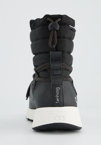 Bottine noire isolée avec un dessus rembourré, dotée d'un système de fermeture à cordon, d'une semelle en caoutchouc texturée et d'un entrepied blanc contrastant.