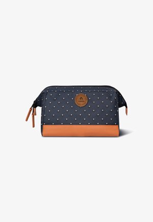 Sacchetto di stoffa blu con pois bianchi, fondo in pelle marrone, cerniera nera e emblema del logo davanti. Design compatto e rettangolare.
