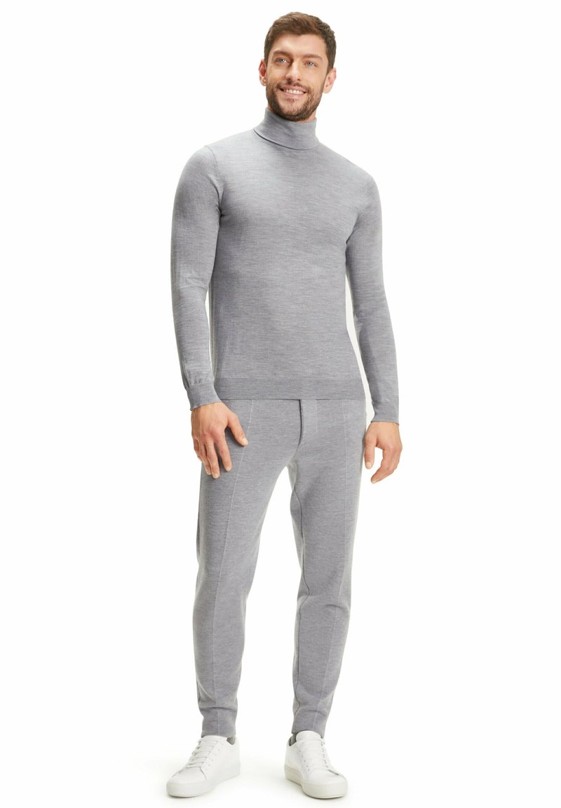 Maglione a collo alto in morbido tessuto grigio e pantaloni affusolati coordinati, con una sottile texture e linee pulite, abbinati a scarpe da ginnastica bianche.