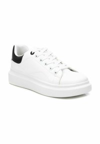 Zapatillas de cuero blancas con acento negro en el talón, puntera redonda y suela de goma plana. Cuenta con seis ojales y un diseño cosido en la parte superior.