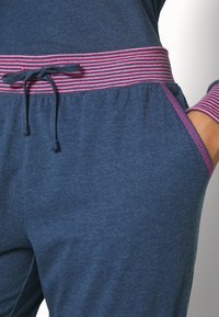 Marineblauwe joggers met een gestructureerde afwerking, met een roze gestreepte tailleband en trekkoord, en zijzakken voor functionaliteit.