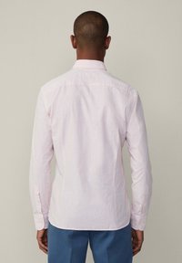 Camicia a maniche lunghe a righe rosa e bianche, con colletto a bottoni e orlo curvo. Tessuto in cotone con una superficie liscia.