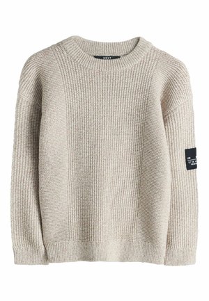 Beiger Strickpullover mit strukturiertem Rippenmuster, rundem Ausschnitt und langen Ärmeln. Mit einem schwarzen Etikett am linken Ärmel.