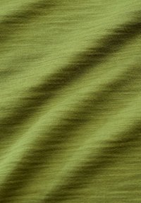 Green woven fabric displaying a soft texture with subtle variations in hue, creating a smooth, undulating surface pattern.