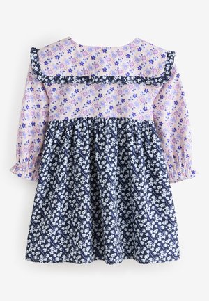 Gėlių raštų suknelė, kurios viršuje šviesiai rožinė su violetiniais raštais, o sijonas tamsiai mėlynas su baltais žiedais, papuošta raukiniais.