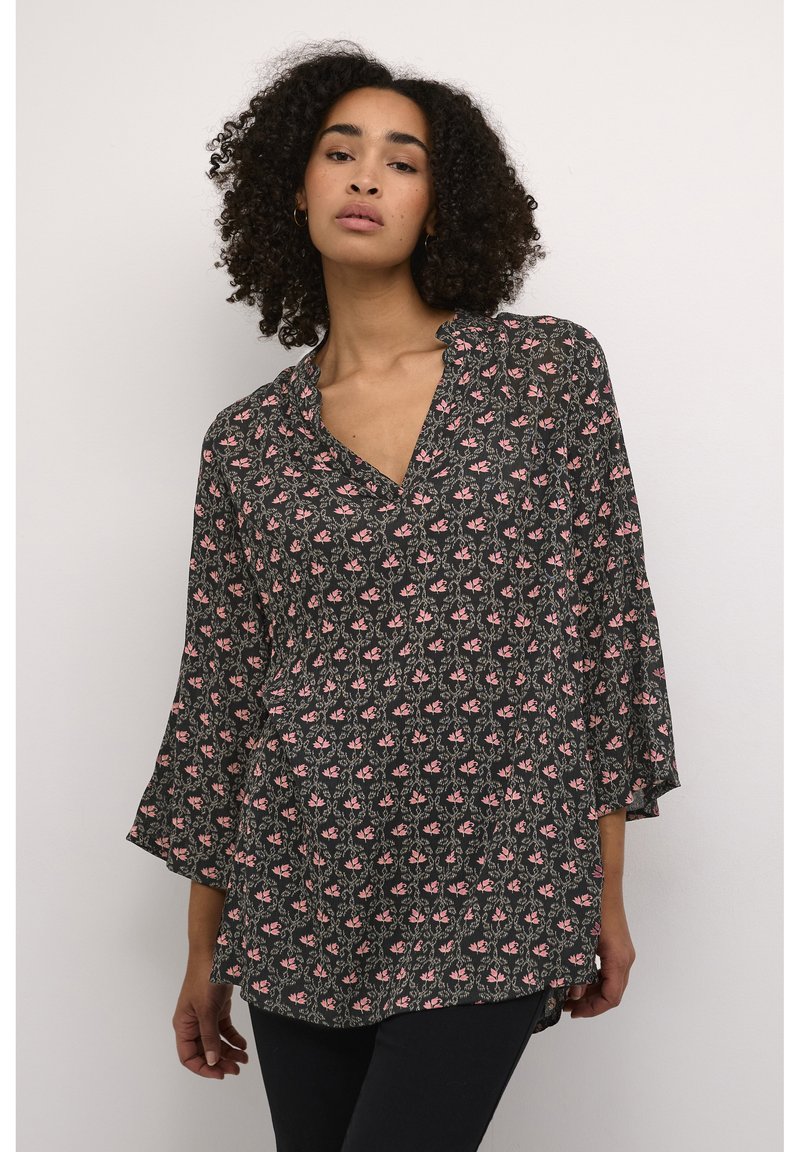 Blouse noire avec un décolleté en V et des manches cloche 3/4, ornée d'un motif floral en rose et vert. Tissu léger avec une coupe ample.