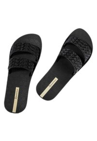 Sandales noires à glissière avec deux brides tissées et une semelle texturée. Présente un logo doré sur une étiquette beige et un motif d'hexagones sur la semelle intérieure.