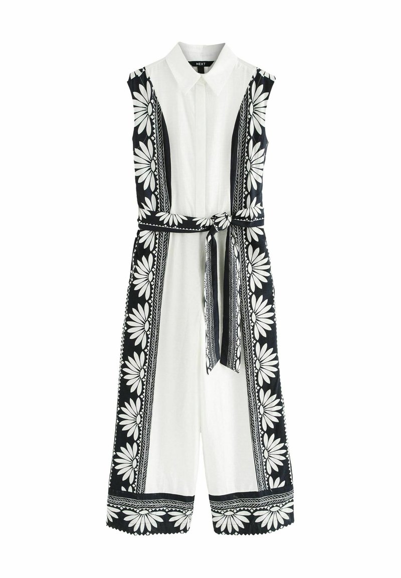 Ärmlös jumpsuit i vitt bomull med svarta blommönster och detaljer. Har en krage, bälte i midjan och vida ben med scallop-erade fållar.