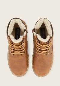 Bruine leren boots met nepbont voering, ronde neus en gouden veters. Voorzien van een ritssluiting en contrasterende stiksels.