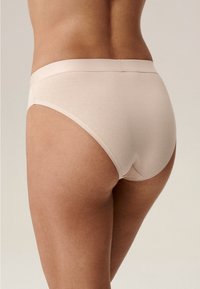 Beżowe bawełniane majtki z miękkim paskiem, o średnim stanie i gładkiej fakturze, podkreślające komfort i dopasowanie.