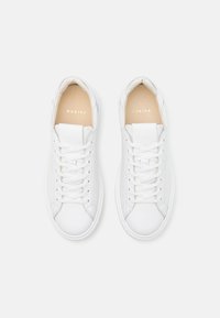 Hvite lær sneakers med rund tå, snøring og diskret merkevare. Slett tekstur med minimalistisk design og polstret krage.
