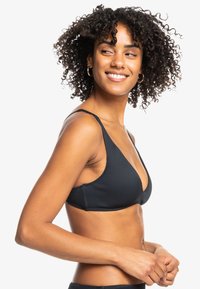 Svart ribbet bikinitopp med trekantet design, tynne justerbare stropper og en glatt tekstur. Minimalistisk stil, ingen utsmykninger.