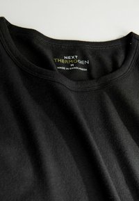 T-shirt nera in cotone con scollo rotondo. Presenta l'etichetta "NEXT THERMOGEN" e le istruzioni per la cura all'interno del collo. Texture liscia.