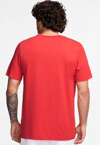 Camiseta corta de manga roja hecha de algodón. Presenta un cuello redondo y un corte recto, con una textura suave y sin patrones o logotipos visibles.