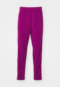 Pantaloni da jogging in pile di un vivace viola con un fit slim, cintura elastica e strisce laterali rosse. Texture liscia, design a caviglia affusolata.