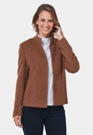 Bruine wolmix jas met een ronde kraag, zes voorknoopjes en een rechte snit, gedragen over een witte top en gecombineerd met een donkere jeans.