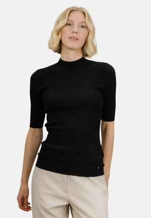 Svart ribbestrikket topp med kort erme, høy hals og tettsittende silhuett, med subtile sømdetaljer og en liten logoakse.
