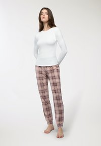 Maglietta a maniche lunghe bianca e pantaloni del pigiama a quadri rosa con accenti grigi. I pantaloni presentano una vita elasticizzata e orli con risvolto.