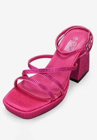 Sandal de tacón alto rosa con múltiples tiras entrelazadas, acabado texturizado, punta cuadrada y un tacón bloque adornado con piedras de strass.