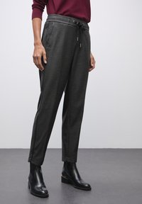 Harmaat muotolehdet, joissa on hienovarainen ruutukuvio, joustava vyötärö ja nauhakuja. Yhdistetty mustien nilkkureiden kanssa.