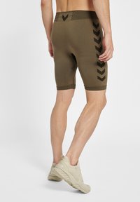 Olivgrüne Sportshorts mit einer enganliegenden Passform, ausgestattet mit einem strukturierten Bund und schwarzen Chevron-Mustern an den Seiten.
